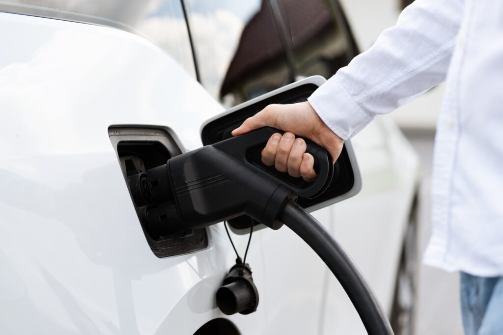Person Charging Electric Vehicle With EV Charger At Home